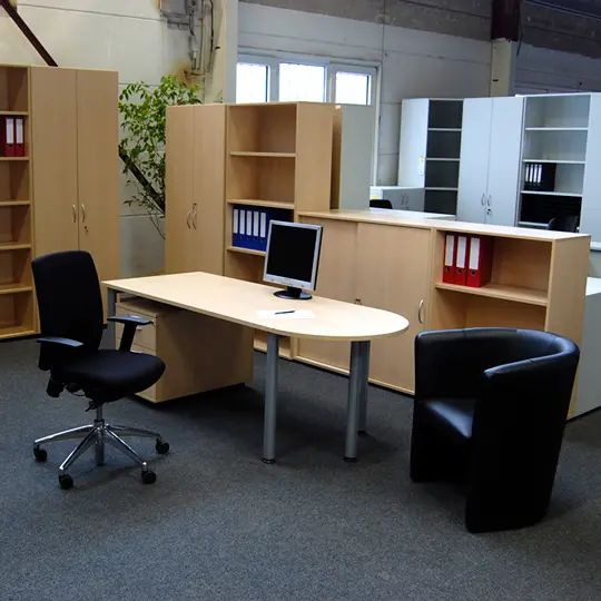 Schreibtisch mit halbrunden Besprechungsanbau, verschieden hohen Aktenschränken, Sideboards in Ahorn Dekor und einem Bürodrehstuhl und Besucherstuhl