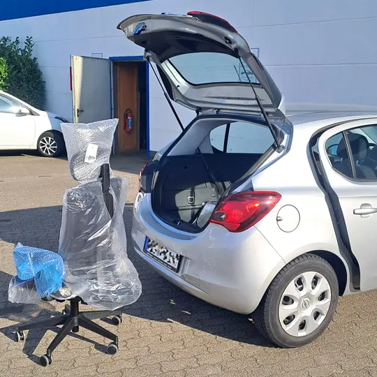 Kunde mit einem neuem Bürodrehstuhl vor seinem Auto Einladen in den Kofferraum 