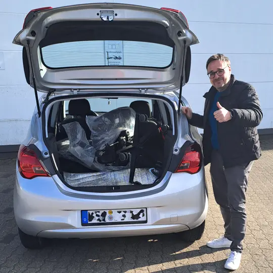 Kunde mit einem neuem Bürodrehstuhl vor seinem Auto Einladen in den Kofferraum 